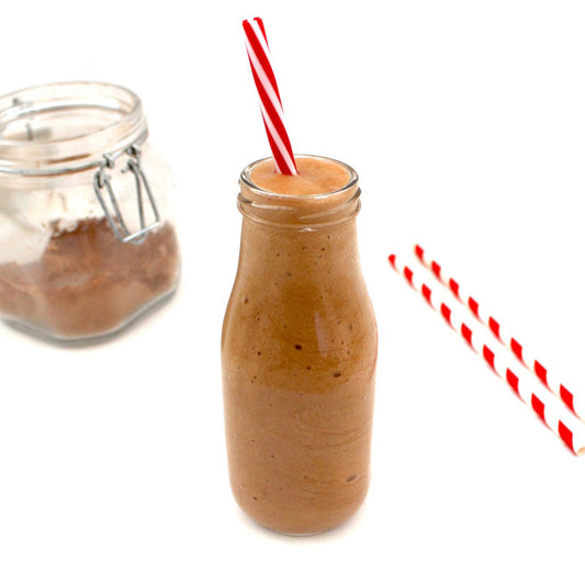 In the center of the image is a clear milk-style bottle filled with VegAnnie's Skinny Mocha Frappuccino, which is sugar-free and keto friendly. Another bottle to the left has a powdered version of the sugar-free frappuccino.