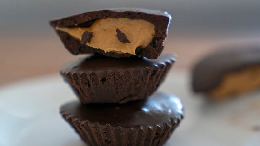 Three sugar-free homemade Reese's style candies are stacked on top of each other. The top one is broken in half displaying a sugar free peanut butter center.