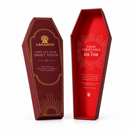 Two coffin-shaped product boxes on a white studio background. One box is shown from the front with a dark red exterior, gold sunburst details, and the brand name LAKANTO.