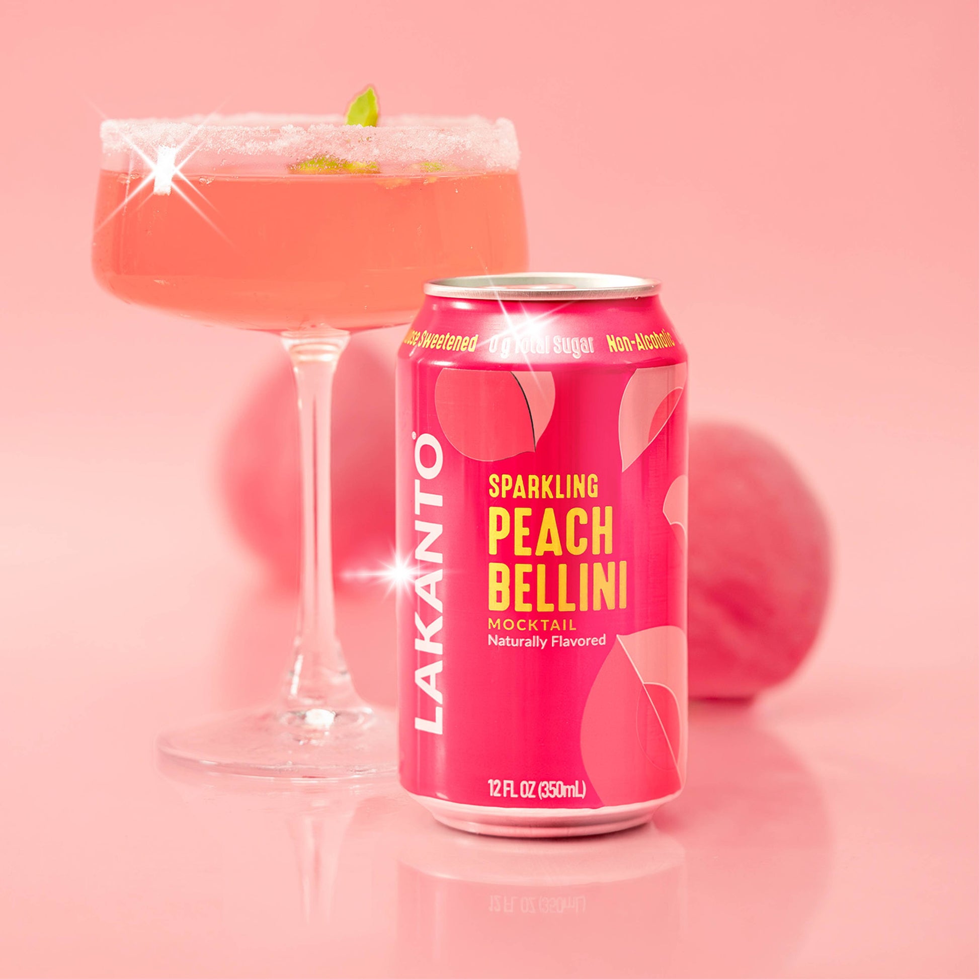 Lakanto Sparkling Peach Bellini Mocktail can with drink poured into a martini cocktail glass a pink background 