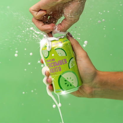 Hand holding and opening  a can of Lakanto Cucumber Mojito Mocktail against a green background. Naturally flavored. Monk fruit sweetener with allulose. Zero sugar. Non alcholic. Low calorie.